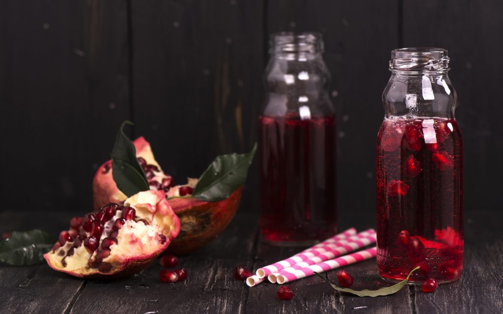 Homemade red pomegranate lemonade in small glass bottles